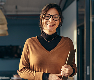 woman smiling and holding a closed laptop